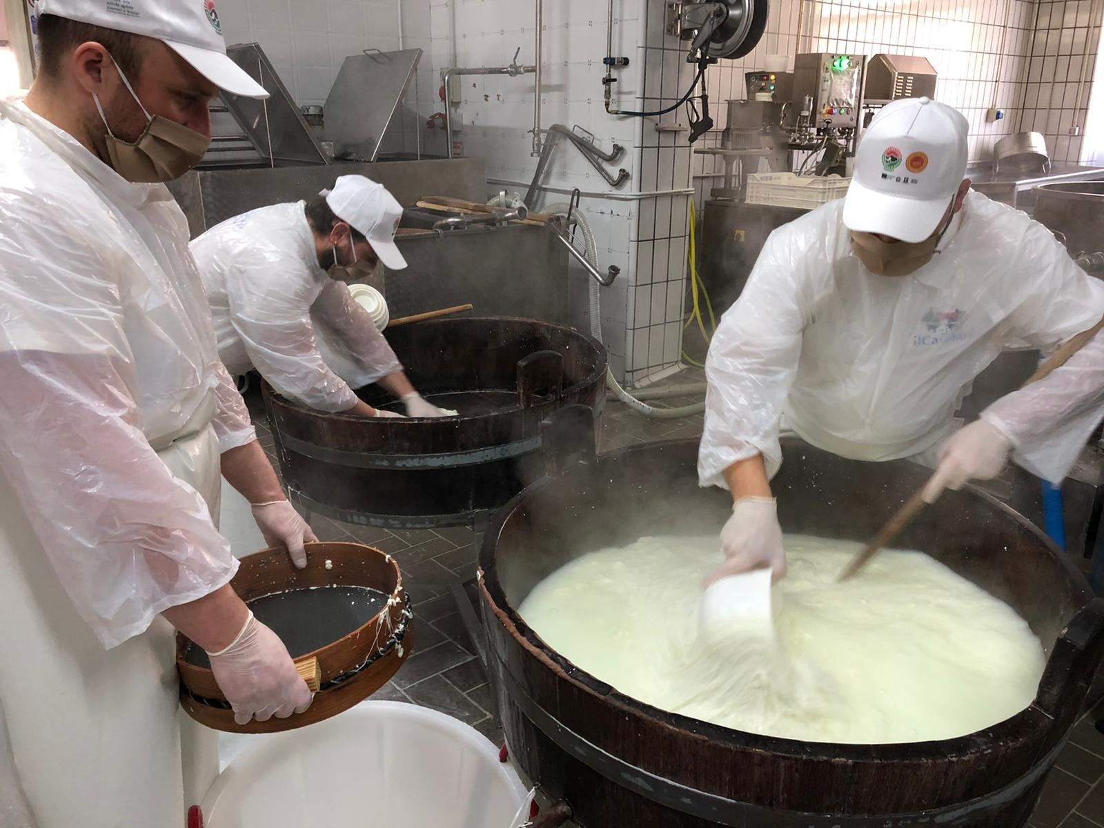 Mãos esticando a massa quente de mussarela de búfala durante a filatura