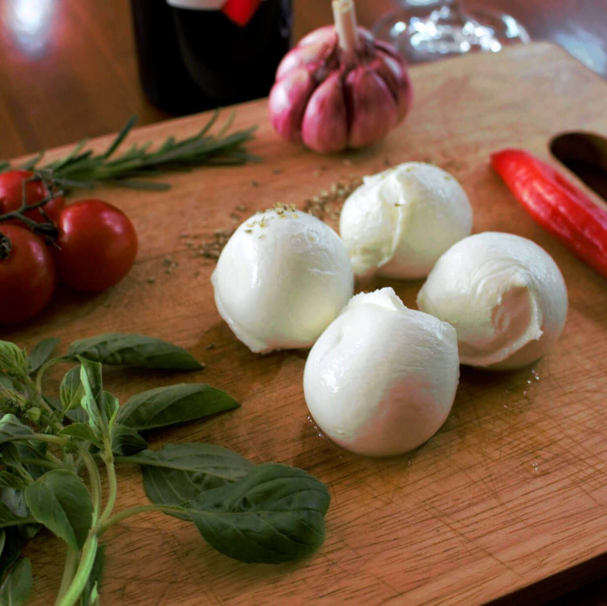 Bocconcini de búfala sobre tábua com manjericão e tomates