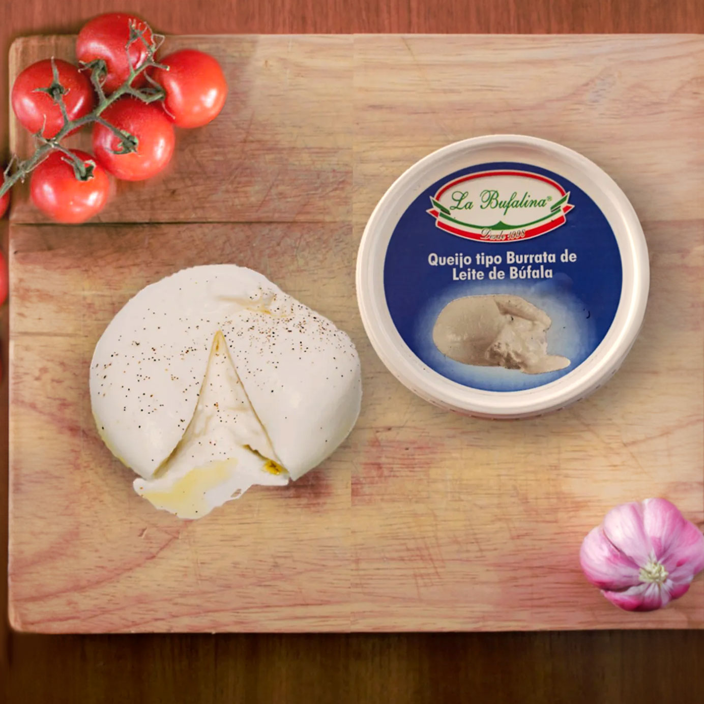 Burrata de búfala aberta sobre tábua, ao lado da embalagem La Bufalina