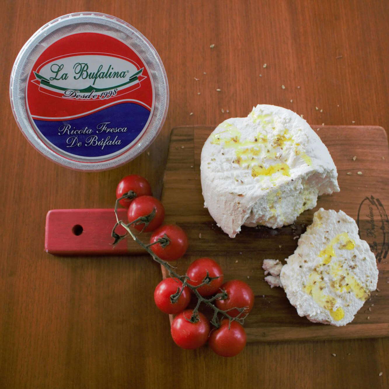 Ricota de leite de búfala aberta sobre tábua, com tomates